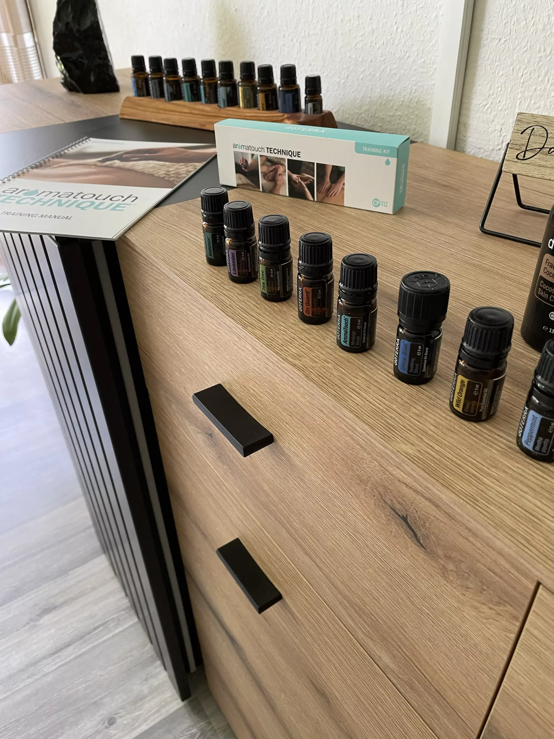 AromaTouch Öle von Jessy Richter mit dem Manual der Aroma Touch Technique auf einer Kommode in Oberfranken