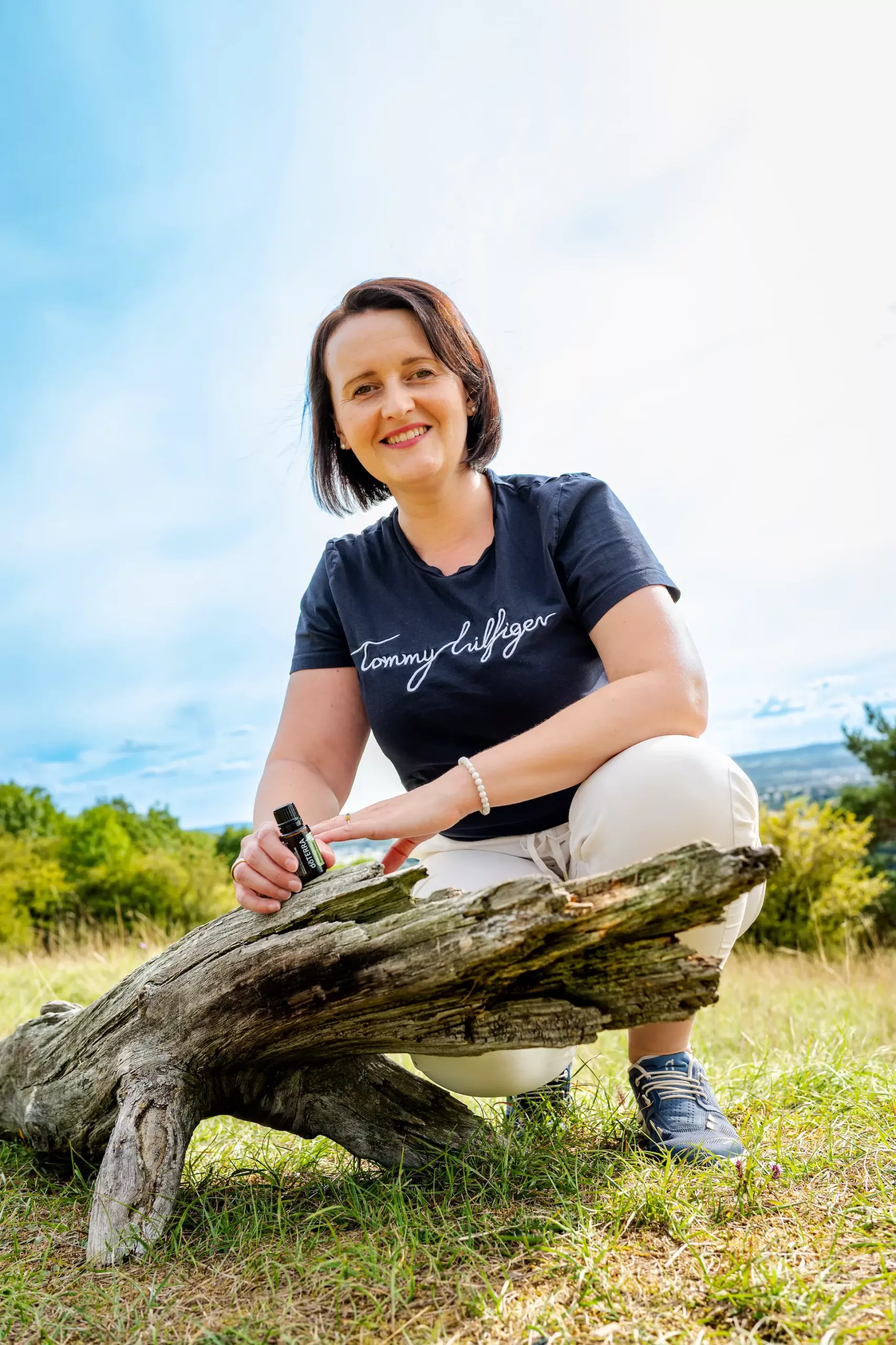 Jessy_Richter_Oelliebe_Kontakt Jessy Richter Ölliebe aus Kulmbach in Oberfranken vor einer Wurzel mit einem Doterra Ölfläschen in der Hand